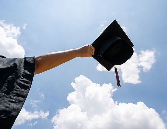 Bild von Alumni, Person hält Oxford Kappe in der Hand